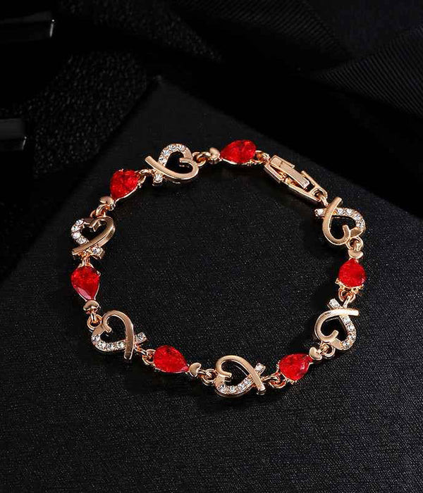 Gold-tone charm bracelet with red heart rhinestone links and heart-shaped clasp