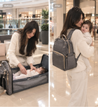 Foldable baby travel bed backpack in dark gray, open with padded mattress and zip pockets